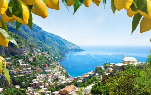 Picturesque view of Positano on Amalfi Coast, Italy, with colorful hillside houses overlooking Mediterranean Sea. Bright yellow lemons in foreground. Welcome to Positano concept 