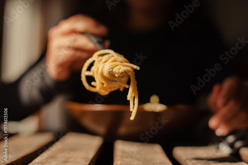 Foto Unrecognizable person with spaghetti wrapped around a fork in the foreground
