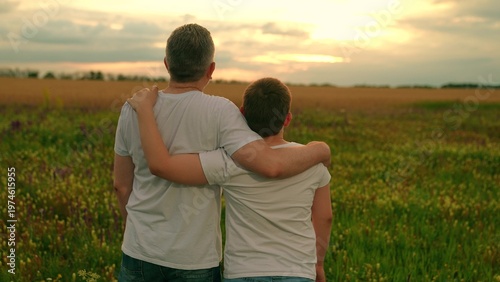 Fényképezés Child son hugs his father in sunny meadow