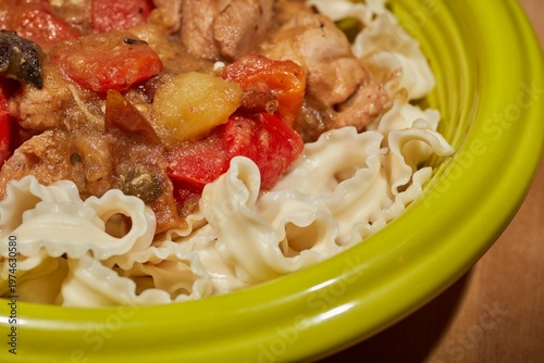 A bowl of big plate chicken on wide noodles.