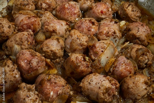 Pieces of pork sausage frying in a skillet