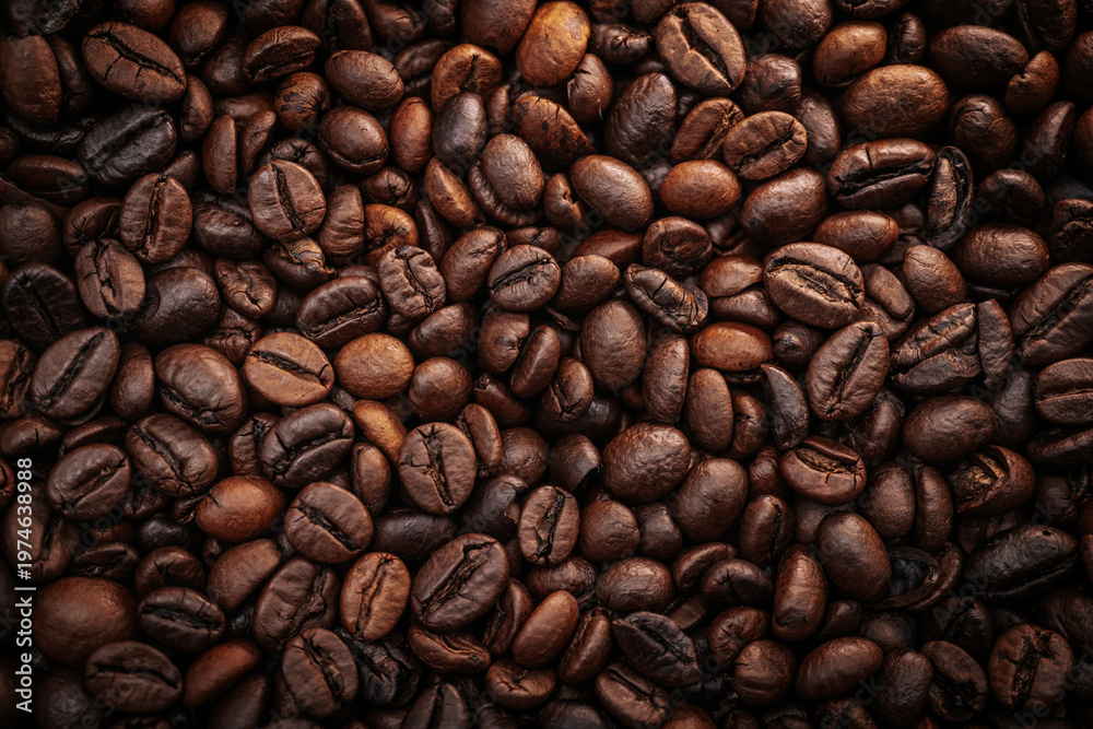 Obraz premium Close-up view of roasted coffee beans showcasing rich textures and varying shades of brown, arranged densely on a dark surface for a natural, organic appearance