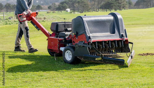 Фотография Groundskeeper aerating golf course green with professional turf maintenance mach