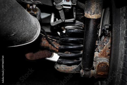 Foto an older vehicle's rear suspension system, specifically showing a shock absorber, a coil spring, and the surrounding chassis components
