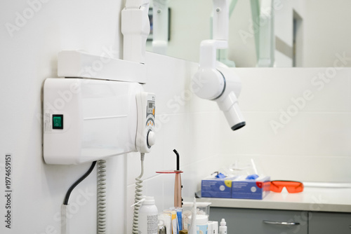Wall mounted dental x-ray unit with digital control panel for diagnostics. Professional medical equipment for teeth imaging and radiology in modern clinical cabinet.