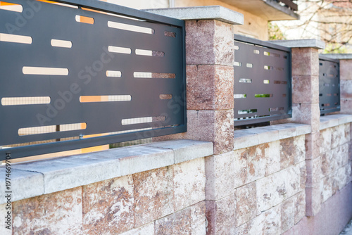 Modern garden fence with perforated metal panels on a concrete block wall