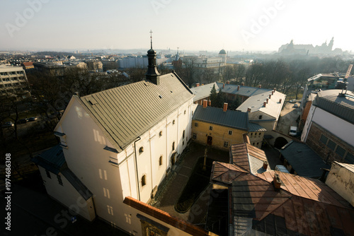 View of historic church and old buildings in Krakow with soft morning haze and city skyline in the background, Poland.