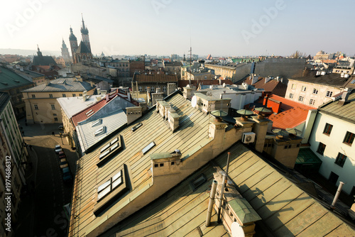 Panoramic view of Krakow old town rooftops with historic buildings and church towers in soft morning light, Poland.
