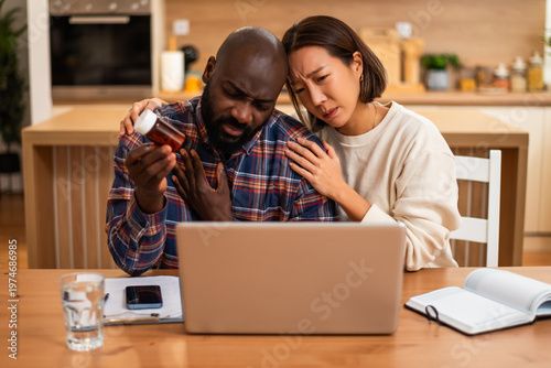 Photography A tense moment shows a couple researching symptoms online, with medication on hand and notes being taken for possible treatment