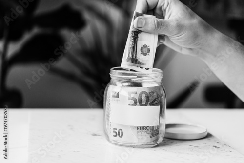 Konstfotografi Saving money in jar, black and white photo
