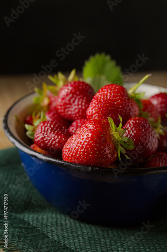 Fresh strawberries in metal bowl on rustic wooden background, close-up