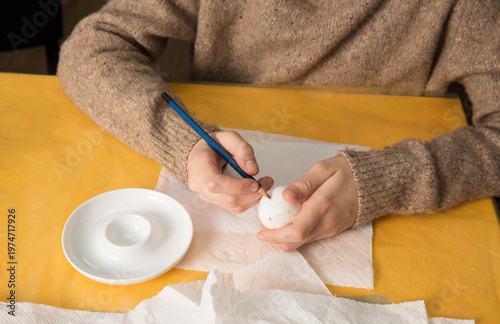 Child drawing traditional pattern on egg for Ukrainian pysanka