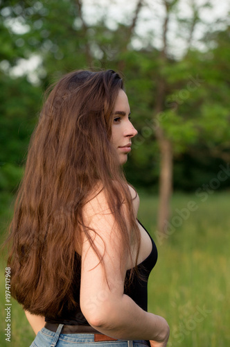 Confident young woman in profile standing in green park