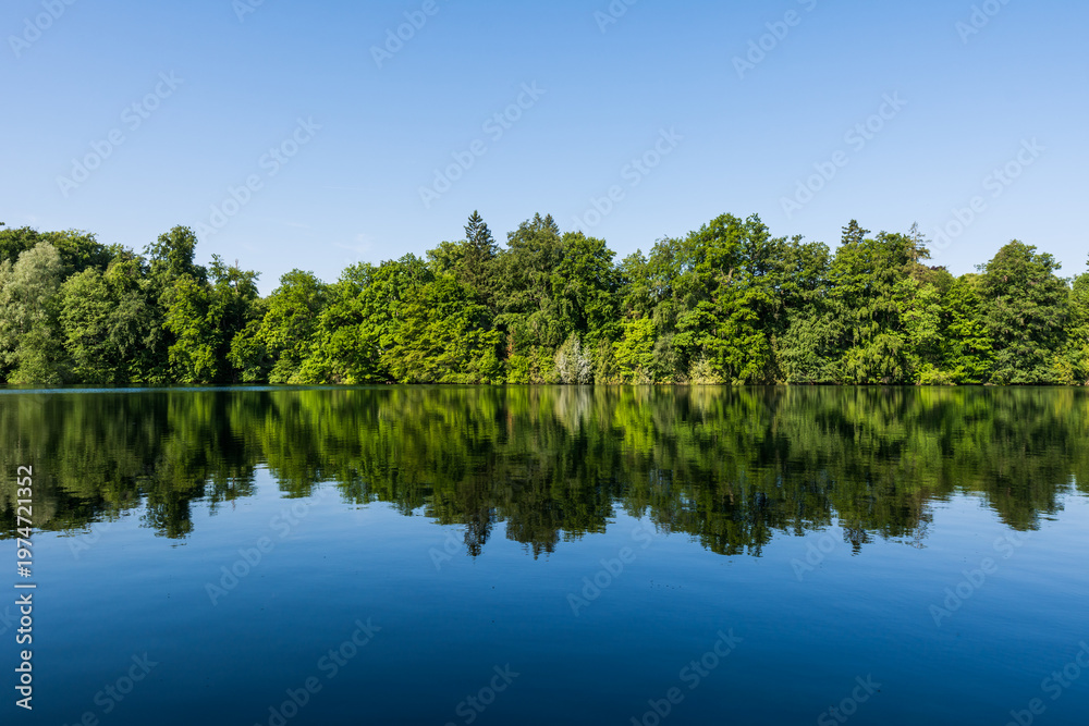 Fototapeta premium Wooden pier overlooking the calm water of Wesslinger See lake in Bavaria, Germany
