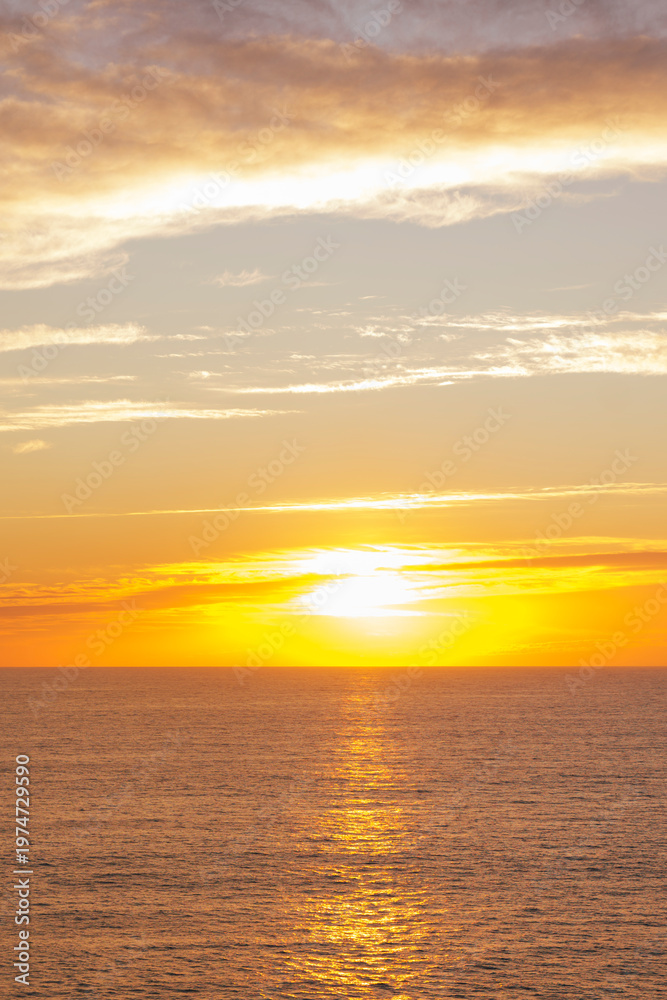 Fototapeta premium Golden sunset over calm ocean horizon with warm sky and copy space