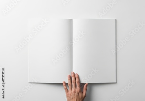 A top view of a person holding an open blank white book centered on a clean minimalist background