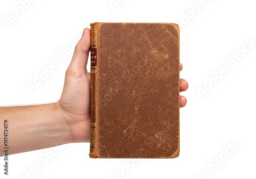 A person holding an antique brown book with a worn cover against a plain white background area.