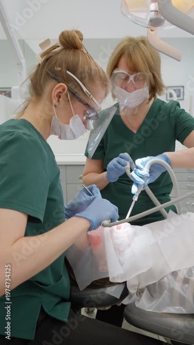 Female dentist cleans patient oral cavity with water air syringe during professional dental hygiene. Dental assistant uses suction tube to remove liquids and ensure safe treatment process