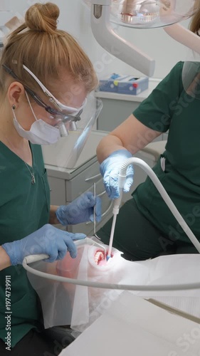 Doctor flushes patient oral cavity with water spray to remove loose calculus fragments. Assistant works with saliva ejector. Dental team finishes professional cleaning session in clinic