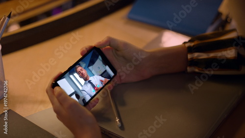 Office manager video calling cellphone having online interview at desk close up.