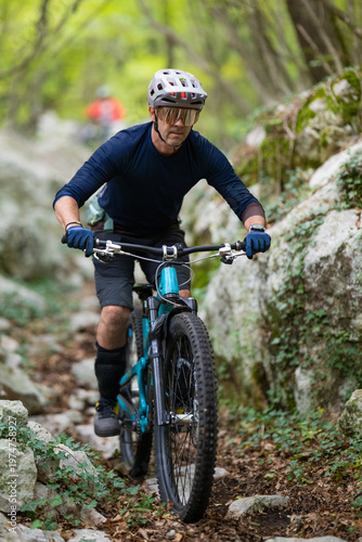 Obraz na płótnie Male mountain biker riding a blue full-suspension bike on a rocky forest trail i