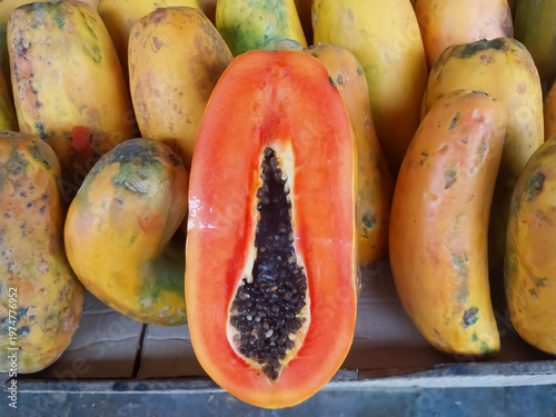 Quadro em tela Fresh ripe papaya cut in half with black seeds on fruit market background