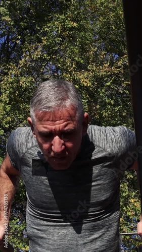 Strong 54-Year-Old Man Doing Parallel Bar Dips -Street Workout. Series Track Code: Fit-Mature-Man-54-Outdoor-Fitness-Series-2024