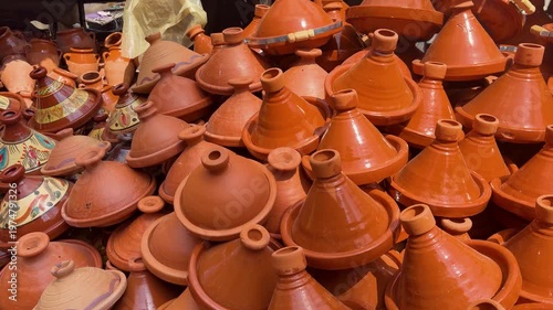 Traditional moroccan tajine pots displayed at a local market in Marrakesh. Many handmade clay tagines with colorful patterns and plain terracotta finish. Authentic pottery souvenirs in Morocco.