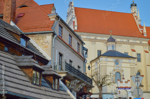 Historical architecture and old buildings with red tile roofs and wooden shingles in the charming town of Kazimierz Dolny under a clear blue sky in Poland.