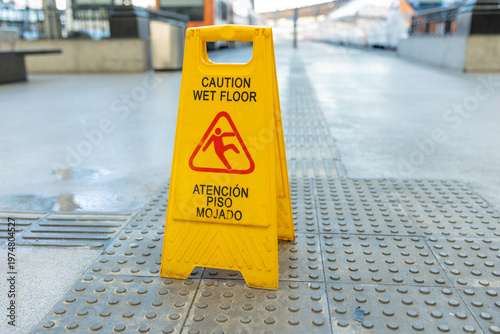 Wet floor caution sign standing on a tiled train station platform, ensuring public safety
