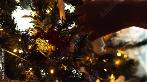 Person hanging white tree ornament on christmas fir