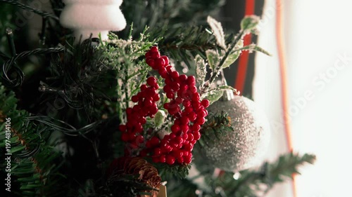 Person decorating christmas tree with red berries