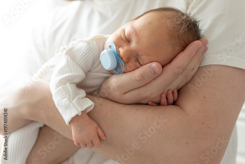Wallpaper Mural Close-up of a newborn baby sleeping peacefully in the arms of a parent wearing a white shirt. The tender moment, soft natural light, and gentle pose convey warmth, safety, and family bonding. Torontodigital.ca