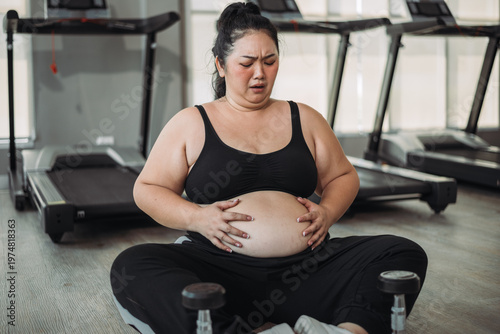 Plus size Asian woman exercises in gym. Beautiful overweight woman in sportswear serious about fat loss in fitness. concept of body positive, self-acceptance, weight loss.