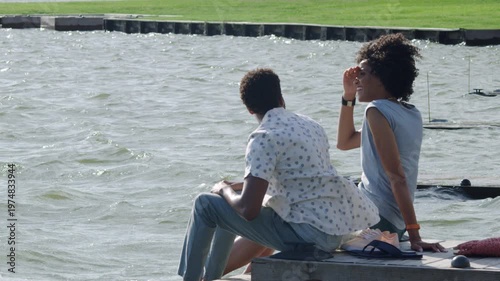 Wallpaper Mural A couple sits and talks on a pier on a windy day as they look out at the choppy water. Torontodigital.ca