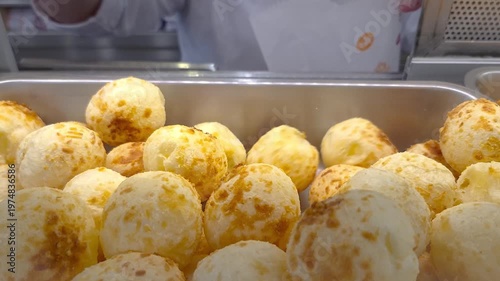 Server picking up several steaming cheese puffs showing off their texture and crispiness.