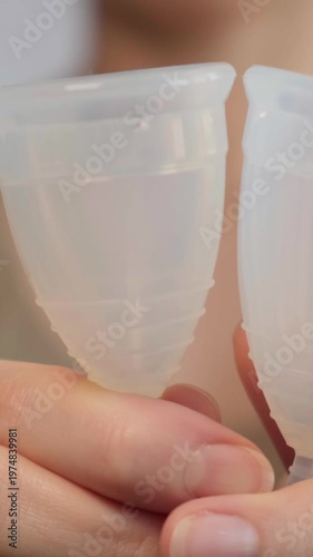 Close-up woman shows menstrual cup in hand. Feminine hygiene products, gynecology and self-awareness. Daily care and the female cycle. Eco in women health, menstruation or period