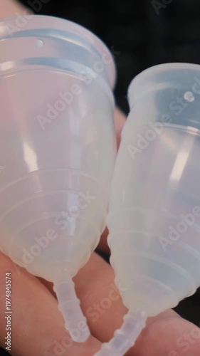 Close-up woman shows menstrual cup in hand. Feminine hygiene products, gynecology and self-awareness. Daily care and the female cycle. Eco in women health, menstruation or period