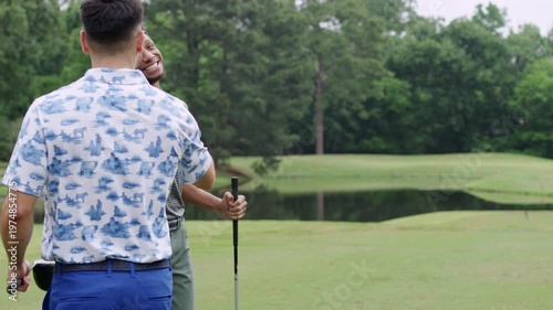 Wallpaper Mural Two male friends fist bump each other as one of them puts a golf ball on a tee to prepare his shot Torontodigital.ca