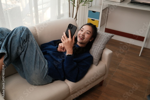 Happy young woman relaxing on sofa using smartphone
