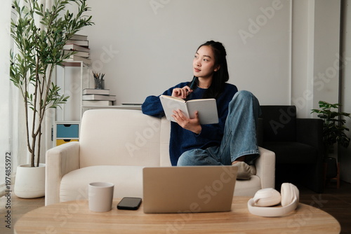 Young woman thinking, writing ideas in home journal