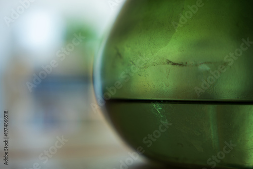Foto Curved green glass vessel with liquid line in soft indoor light