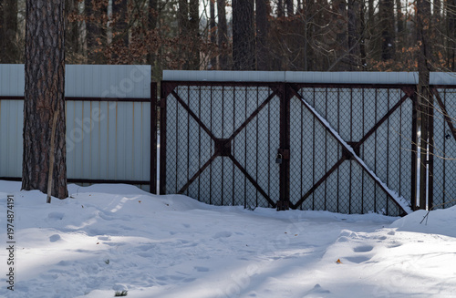 The gate and fence are covered with snow.