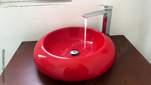 Bathroom red sink, faucet with running water. Saving resources, utility bills. Water resources, water cost