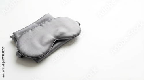 Smooth gray satin sleep mask rests on neatly folded matching fabric against a clean white background