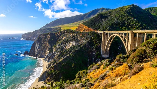 Scenic coastal landscape with a bridge over a rocky shoreline, mountains, and ocean under a blue sky