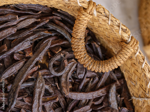 Photos Carob pods filling a woven basket