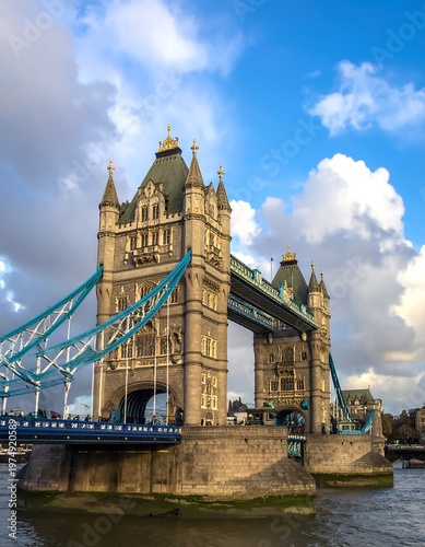 A tall, stone bridge against a bright blue sky filled with fluffy white clouds, casting a slight shadow on the bridge