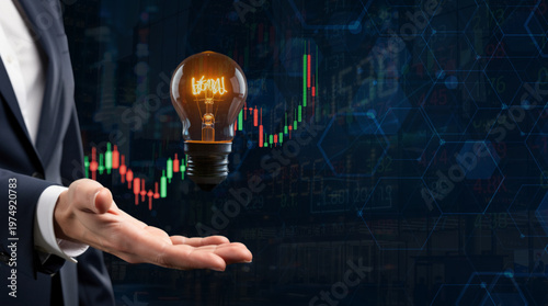 businessman holding glowing light bulb over rising stock market candlestick chart on tech background