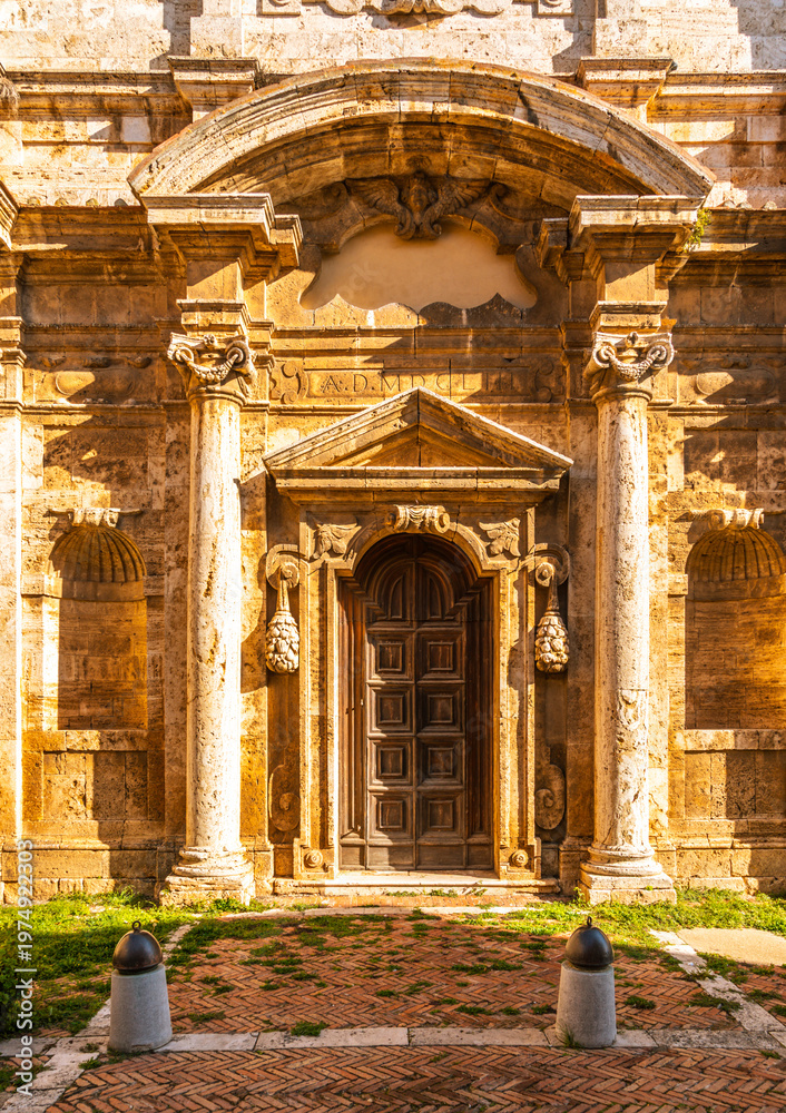 Fototapeta premium Ornate stone facade featuring ancient wooden door in Montepulciano, Italy.